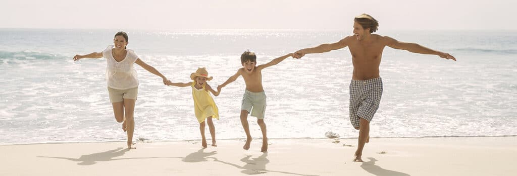 Familie mit zwei Kinder gluecklich am Strand