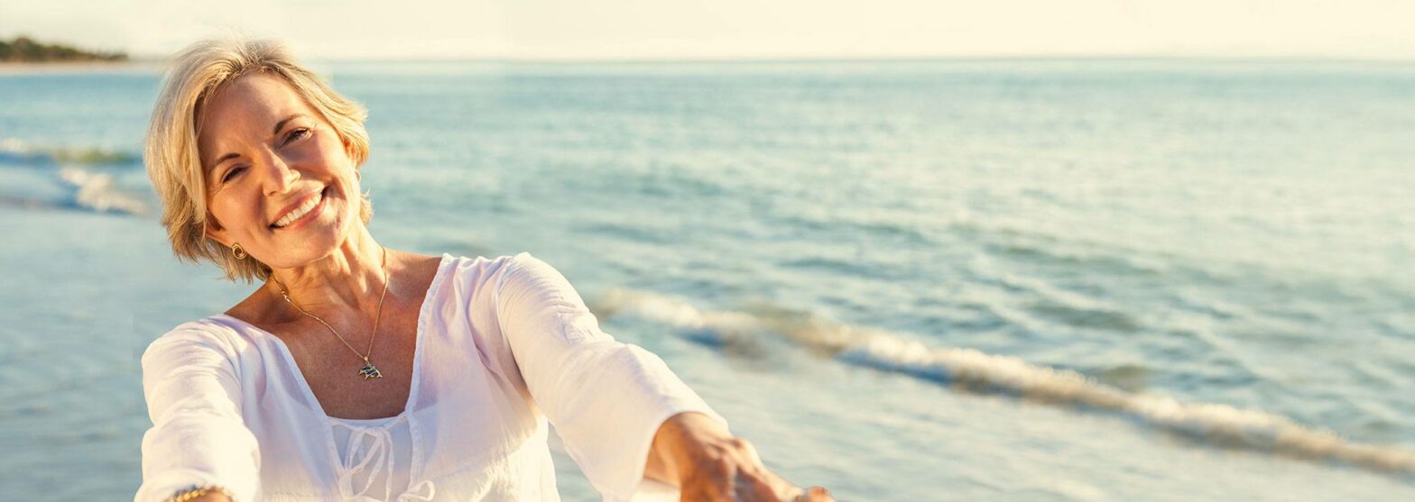 Laechelnde aeltere Dame am Strand