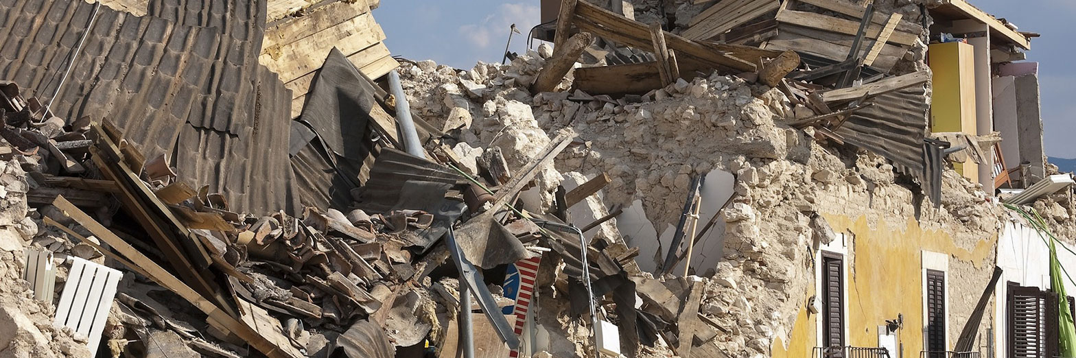 Zerstörte Gebäude nach einer Katastrophe mit sichtbaren Trümmern, einschließlich zerbrochener Balken, Betonbrocken und verstreuten Haushaltsgegenständen, die ein Bild der Verwüstung zeigen.